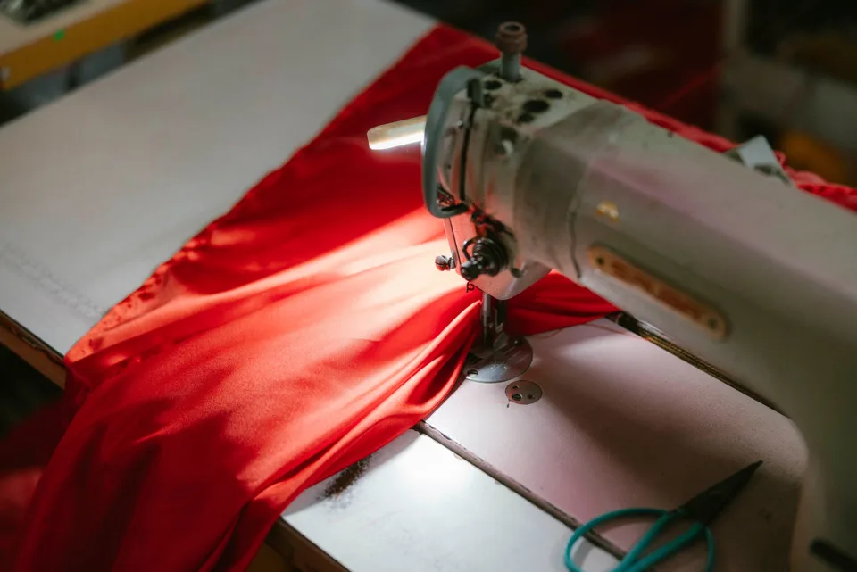 Machine à coudre industrielle installée sur sa table avec un tissu d'ameublement sous le pied presseur
