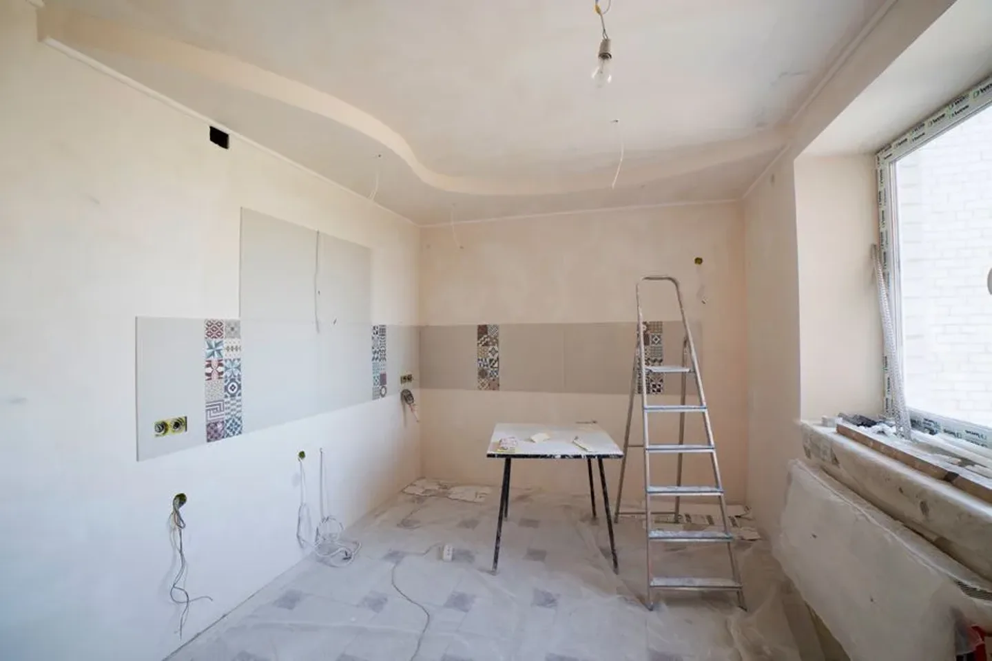 Pièce en cours de rénovation avec échelle et outils posés au sol.